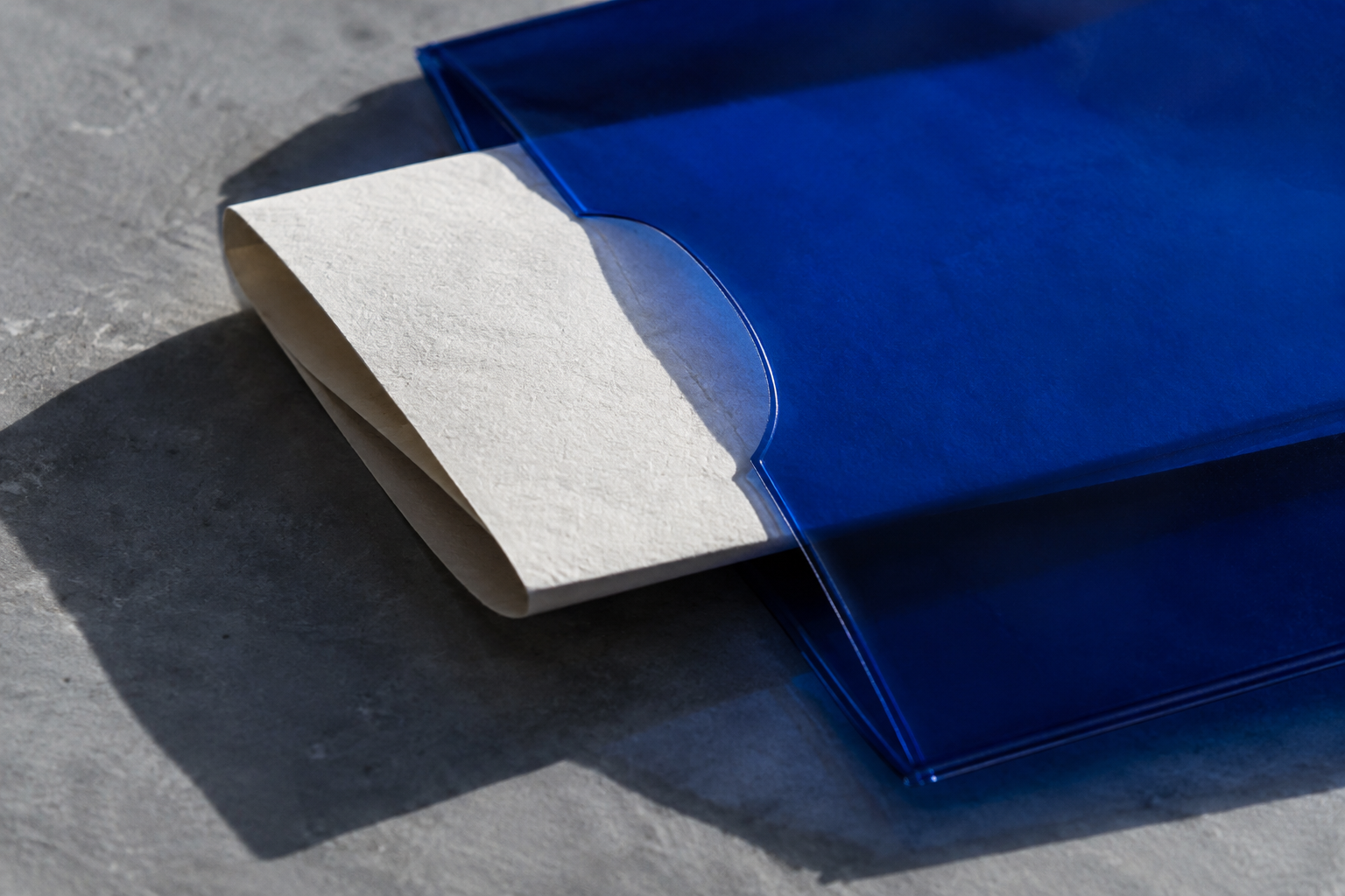 Editorial photograph of folded paper protected inside a translucent cobalt sleeve